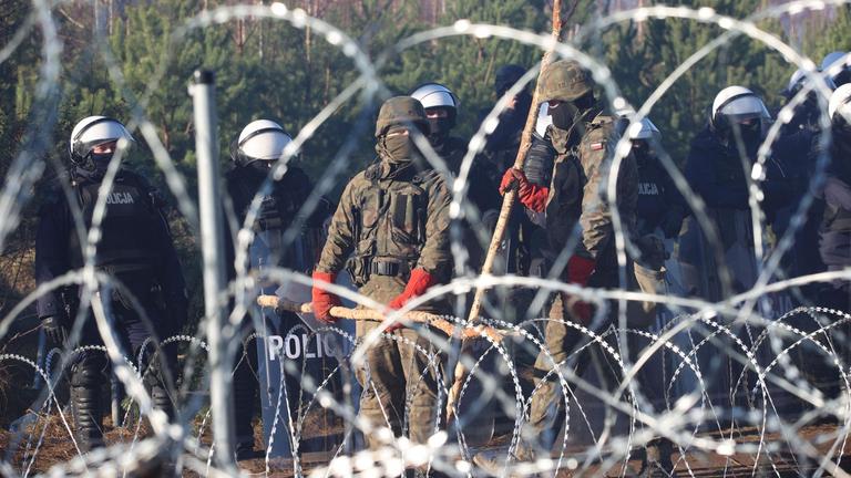 Polnische Sicherheitskräfte hinter Stacheldraht an der Grenze zu Belarus