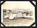 "Camp Borden"- photograph of a Curtiss JN-4 aircraft (number C502, with fleur-de-lis and roundel insignia) on the ground next to a hangar building. There is one man in the rear seat, one holding the (7980804878).jpg